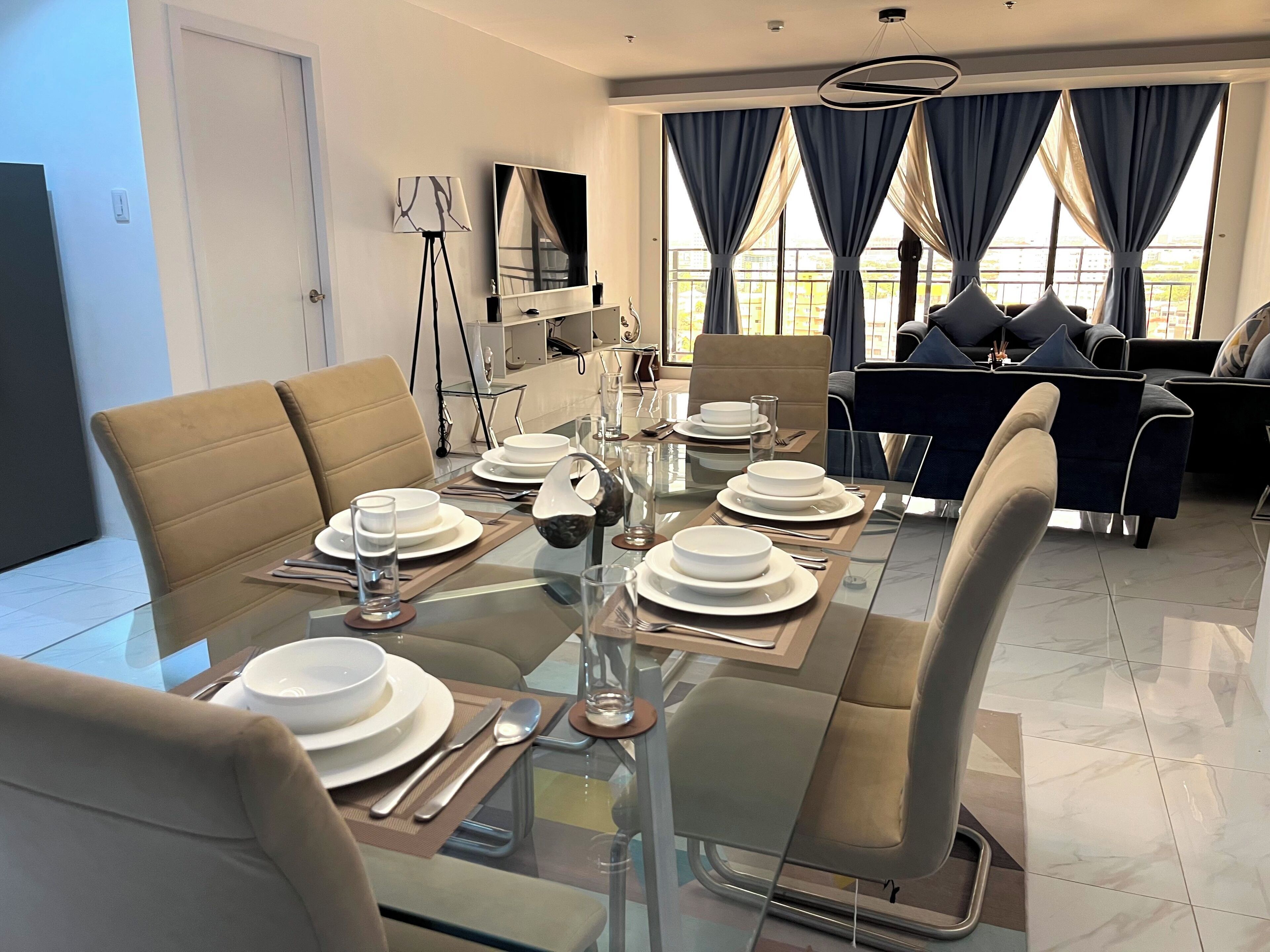 Un comedor moderno con una mesa de vidrio dispuesta para cuatro personas, rodeado de asientos cómodos.