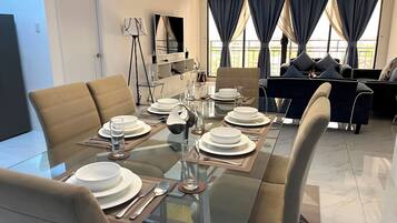 Un comedor moderno con una mesa de vidrio dispuesta para cuatro personas, rodeado de asientos cómodos.