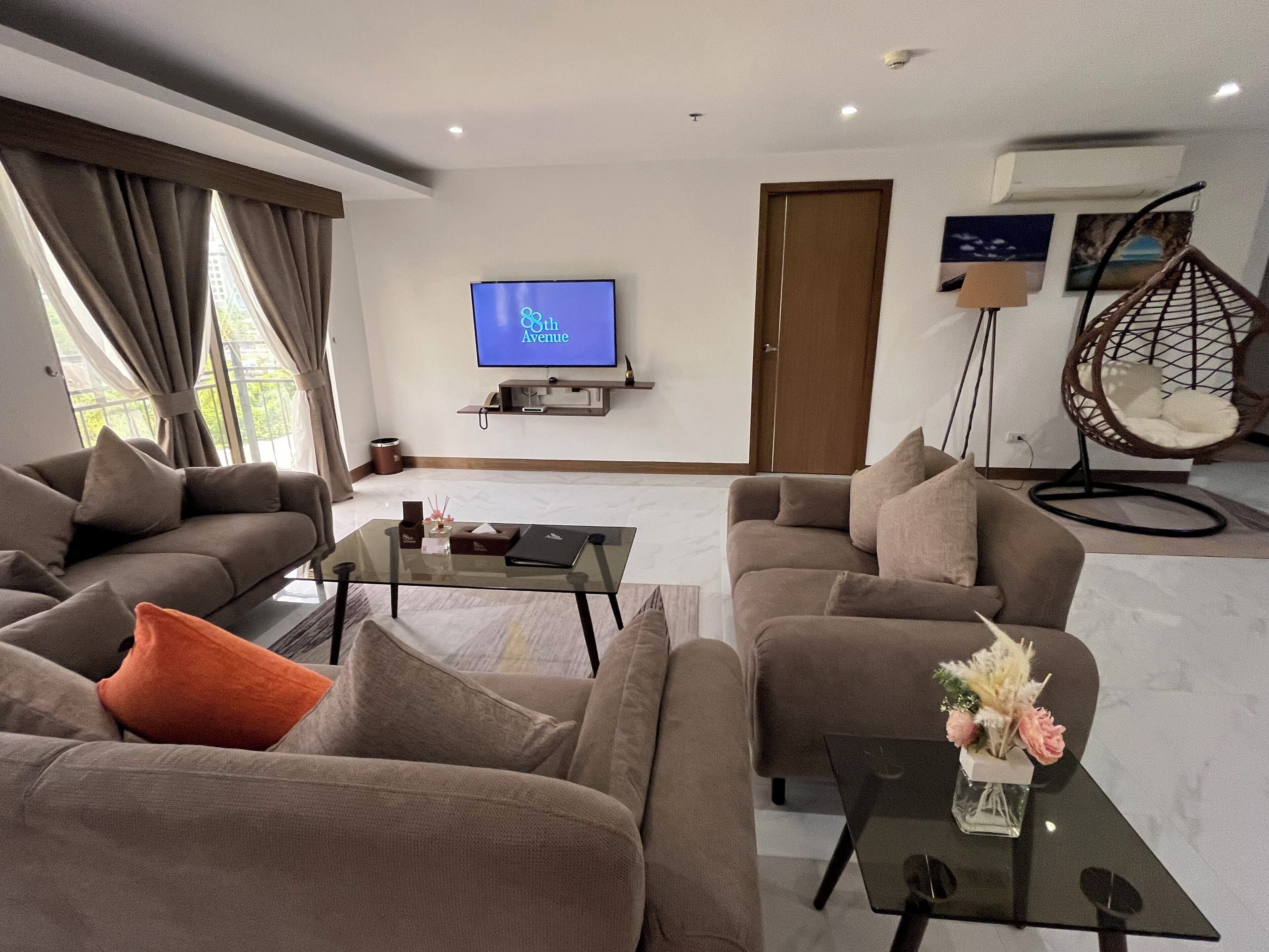 A modern living room with two sofas, a coffee table, a TV, and a hanging chair.