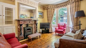 A traditional living room with a fireplace, a television, and seating. - 7 St John's Crescent -  a family break that sleeps 6 guests  in 3 bedrooms (York)