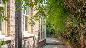 A narrow brick pathway flanked by a building with windows and a wall covered in greenery. - 7 St John's Crescent -  a family break that sleeps 6 guests  in 3 bedrooms (York)