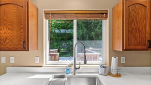 A kitchen with a window, wooden cabinets, a stainless steel sink, and a window blind. - Mt. Rainier Cabin-Hot Tub-AC-Quiet (Packwood)