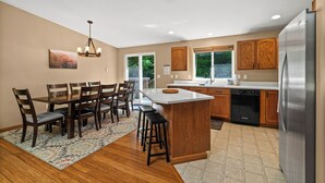 A modern kitchen with wooden cabinets, a central island, and a stainless steel refrigerator. - Mt. Rainier Cabin-Hot Tub-AC-Quiet (Packwood)