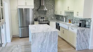 A modern kitchen with white cabinets, a stainless steel refrigerator, a built-in oven, and a marble island. - 5 Min walking to the beach Luxury pool and Jacuzzi (Hollywood)