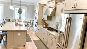Cocina moderna con una isla central, electrodomésticos de acero inoxidable y suelo de madera clara.