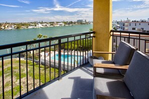 A balcony with a view of a swimming pool and a body of water.