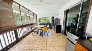 A covered outdoor area with a table and chairs, a refrigerator, and a sliding glass door. -  Unique getaway, 3-bedroom tropical paradise in the heart of Hilo town (Hilo)