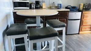 Eine moderne Küche mit weißer Arbeitsplatte, einer Kaffeemaschine, einem Toaster und einem Kühlschrank.