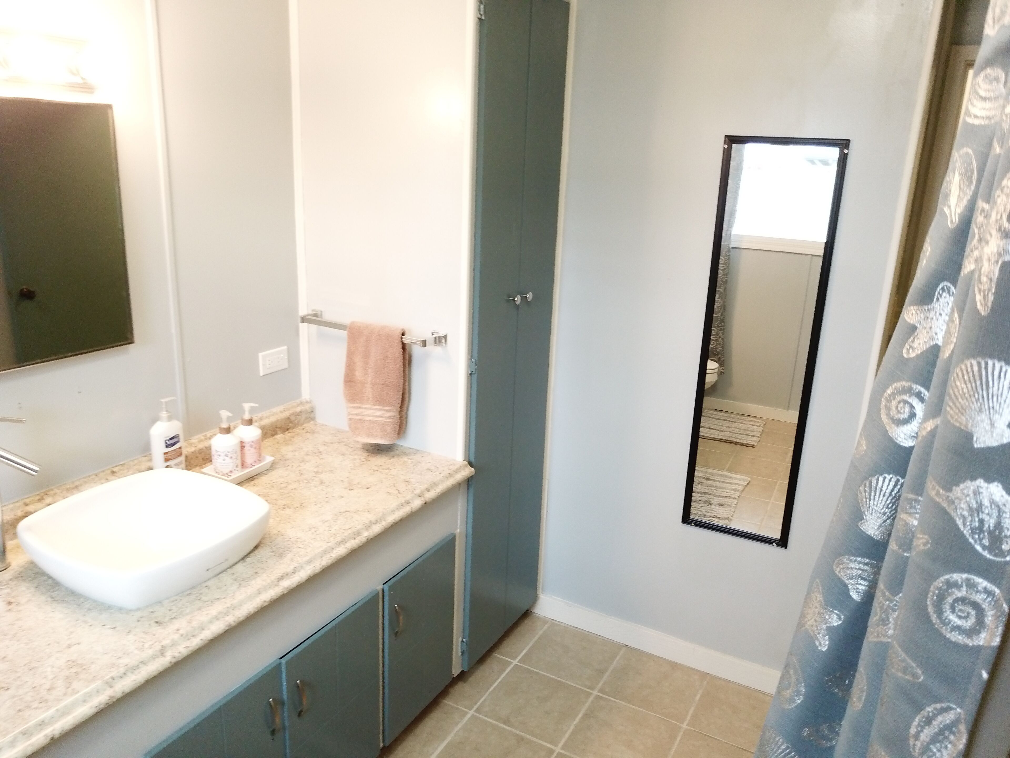 A bathroom with a sink, mirror, towel rack, and shower curtain.