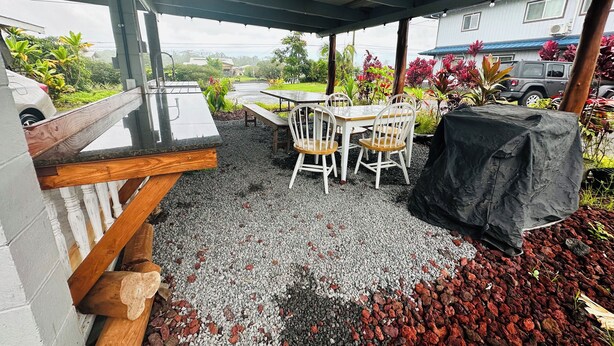 Eine Terrassengruppe im Freien mit Grill, Sitzgelegenheiten und einem überdachten Bereich mit Blick auf eine Wohngegend.