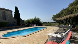 Ein Schwimmbecken mit gefliestem Boden und Liegestühlen.