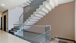 Una escalera moderna con barandillas de vidrio y piso pulido.