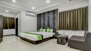 Una habitación de hotel moderna con una cama grande, un sofá, una mesita y aire acondicionado instalado en la pared.