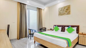 A hotel room with a bed, a desk, a chair, and a door leading to a balcony. - Treebo Sai Village Gold Souk - Sec 43 (Gurugram)