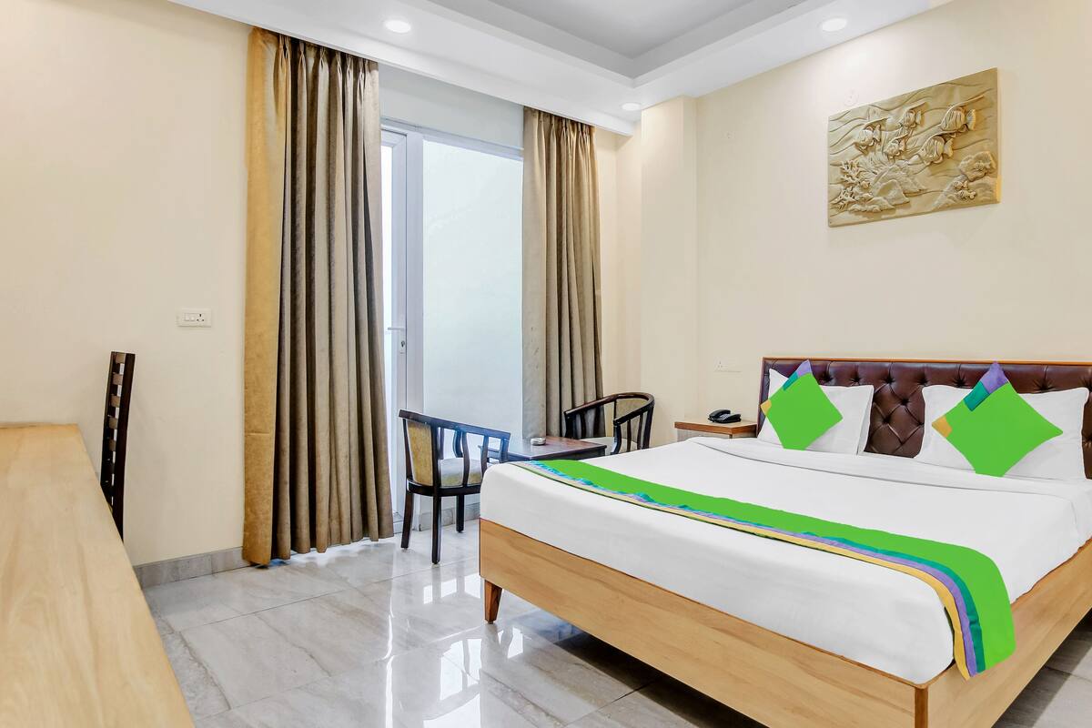 Une chambre d’hôtel comprenant un lit, un bureau, une chaise et une porte donnant sur un balcon.