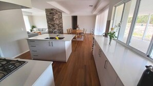 Eine moderne Küche mit einer zentralen Kochinsel, Holzboden und einer Wand mit Steinverkleidung.