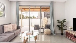 A modern living room with a sofa, a glass coffee table, and a TV stand. - Blue Haven Retreat - Beverly Hills 208 (Beverly Hills)
