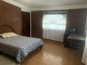 Cozy retreat with a single bed, television, and window with a sheer curtain.