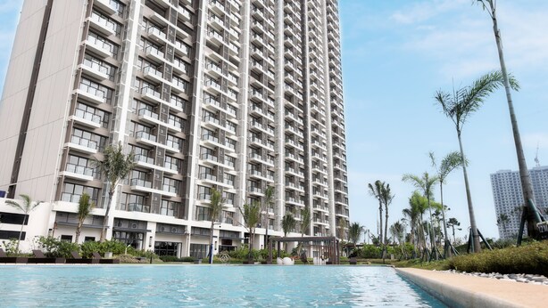 A high-rise residential building with multiple balconies, a swimming pool, and palm trees.
