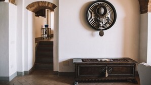 Un couloir avec un escalier, une assiette décorative accrochée au mur et un meuble en bois.