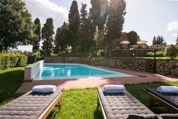 A swimming pool with lounge chairs and a stone wall.