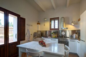A kitchen with a marble countertop, white cabinets, a stove, and a window with a view of the outside.