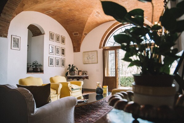 A cozy living room with a high arched ceiling, a fireplace, and a large window.