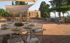 An outdoor dining area with a table set for four, surrounded by wicker chairs and a large canopy.