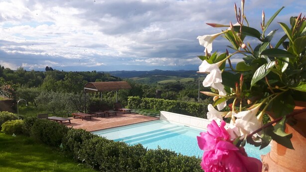 Une piscine offrant une vue sur un paysage rural, entourée de verdure et agrémentée d’un belvédère.