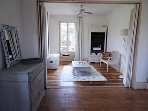 A room with a wooden floor, white furniture, a ceiling fan, and a view through a window. - Character villa, 5 minutes walk from the city center (SARLAT LA CANEDA)