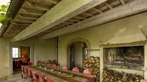 A rustic dining area with a long wooden table, red chairs, and a stone fireplace. - Superb villa in Val d'Orcia. heated pool. design interiors (Sarteano)