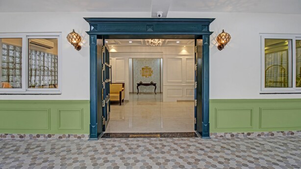Een hotelentree met een groen-wit kleurenschema, een betegelde vloer en een kroonluchter.