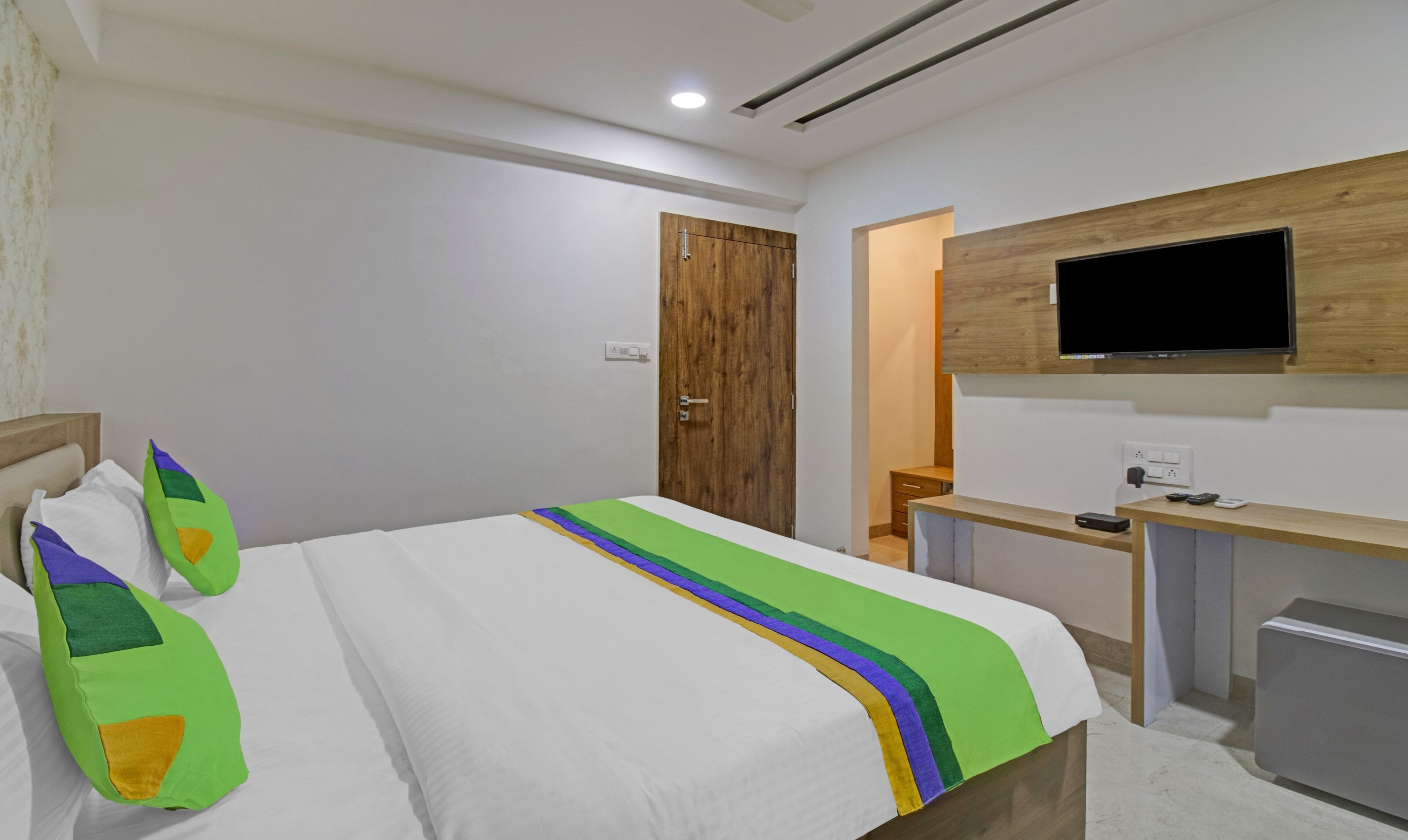 A hotel room with a bed, a desk, a TV, and a wardrobe.