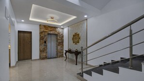 Een modern interieur met een marmeren vloer, een houten deur, een stenen muur en een trap met metalen leuningen.