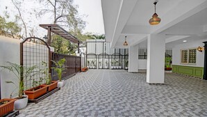 Een ruim terras met betegelde vloer, plantenpotten en een metalen poort.