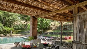 Un espace piscine extérieur doté d’un patio couvert, de marches en pierre et de tables de pique-nique.