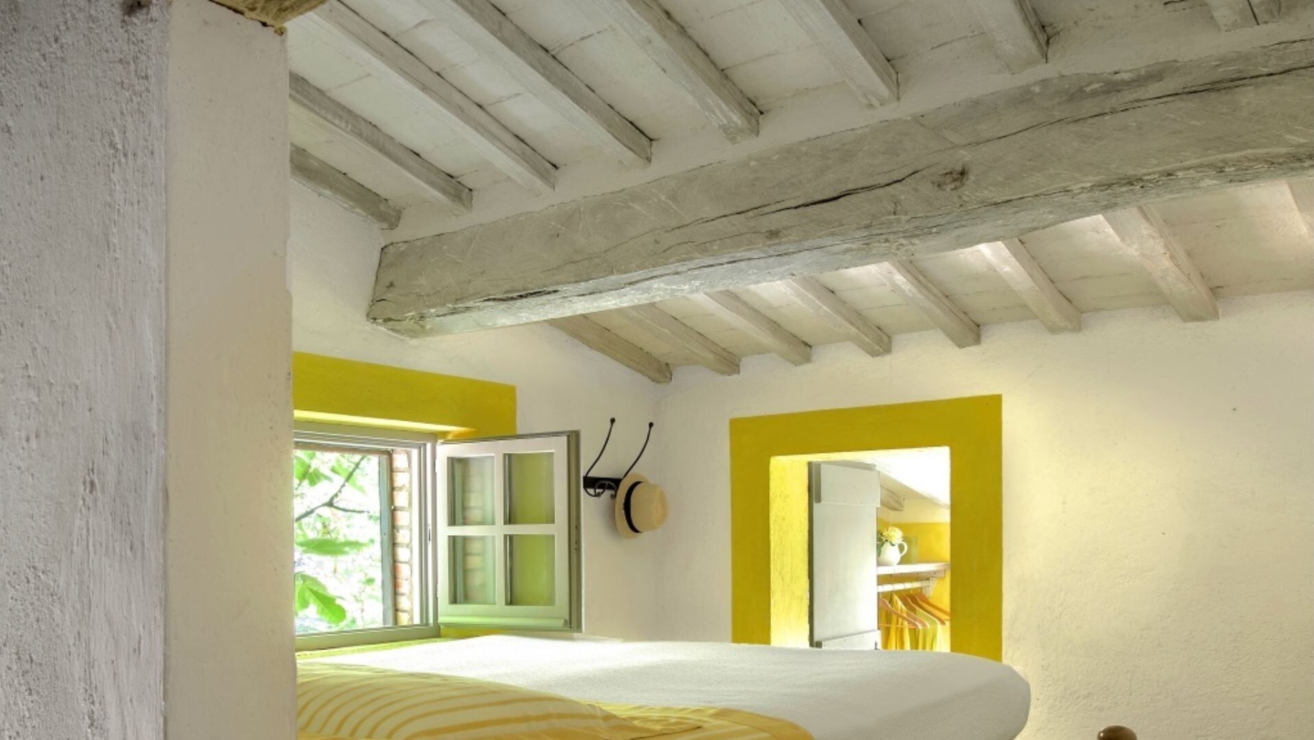 Ein Schlafzimmer mit Bett, Fenster und einer Tür zu einem anderen Raum.