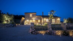 A stone house with a gravel driveway, a stone fence, and a tree in the foreground. - Splendid Villa with big mediterranean garden. Pool, heated jacuzzi, fishing pond (Trevinano)