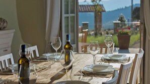 A dining table set for two with wine glasses and bottles, overlooking a scenic view with mountains and a garden. - Splendid Villa with big mediterranean garden. Pool, heated jacuzzi, fishing pond (Trevinano)