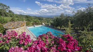 A swimming pool surrounded by lush greenery and a stone structure. - Beautiful villa in the heart of Mugello. Pool, jacuzzi, sauna. (Borgo San Lorenzo)