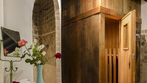A bathroom with a wooden shower enclosure, a mirror, and a vase with flowers. - Beautiful villa in the heart of Mugello. Pool, jacuzzi, sauna. (Borgo San Lorenzo)
