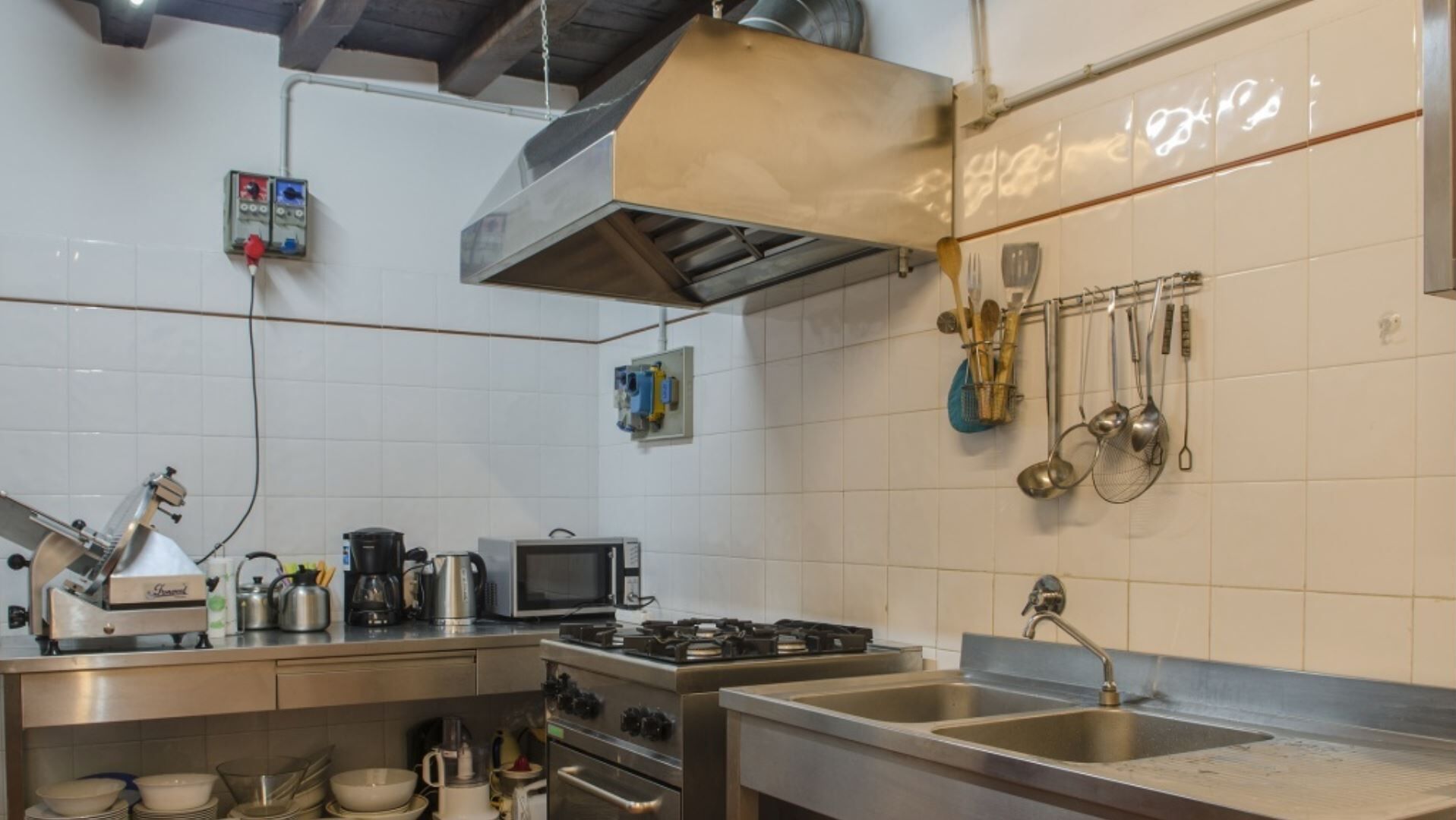 A modern kitchen with stainless steel appliances, a microwave, and a gas stove. There are hanging utensils and a coffee maker on the counter.
