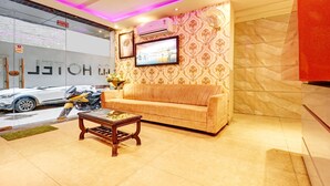 A lobby with a sofa, a coffee table, and a wall-mounted TV. - Itsy Hotels Unique (Amritsar)