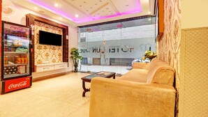 A hotel lobby with a Coca-Cola refrigerator, a sofa, a coffee table, and a large window with a view of the street. - Itsy Hotels Unique (Amritsar)