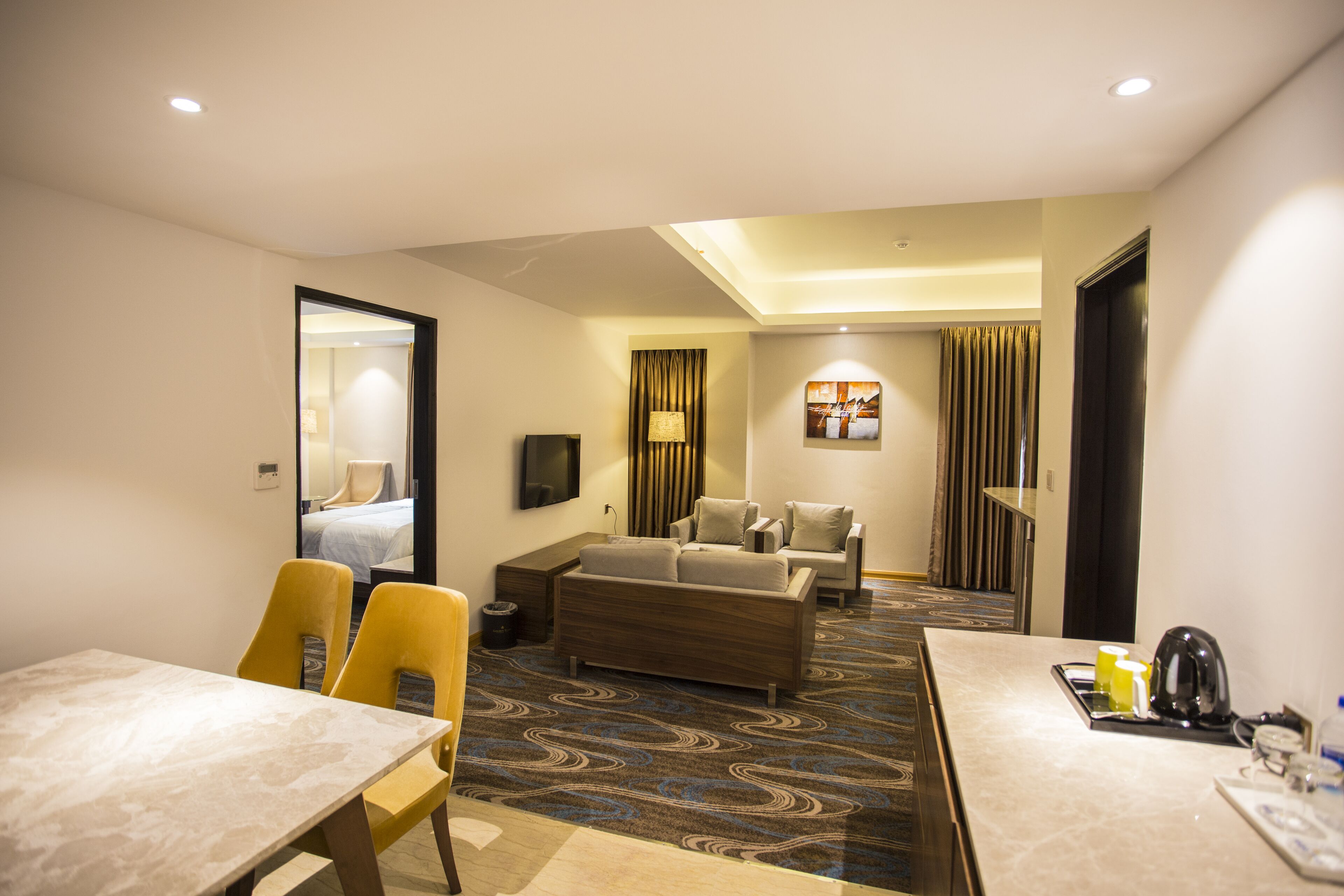 Une chambre d’hôtel comprenant un coin repas, un canapé, une télévision et une moquette à motifs.