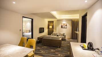 Une chambre d’hôtel comprenant un coin repas, un canapé, une télévision et une moquette à motifs.