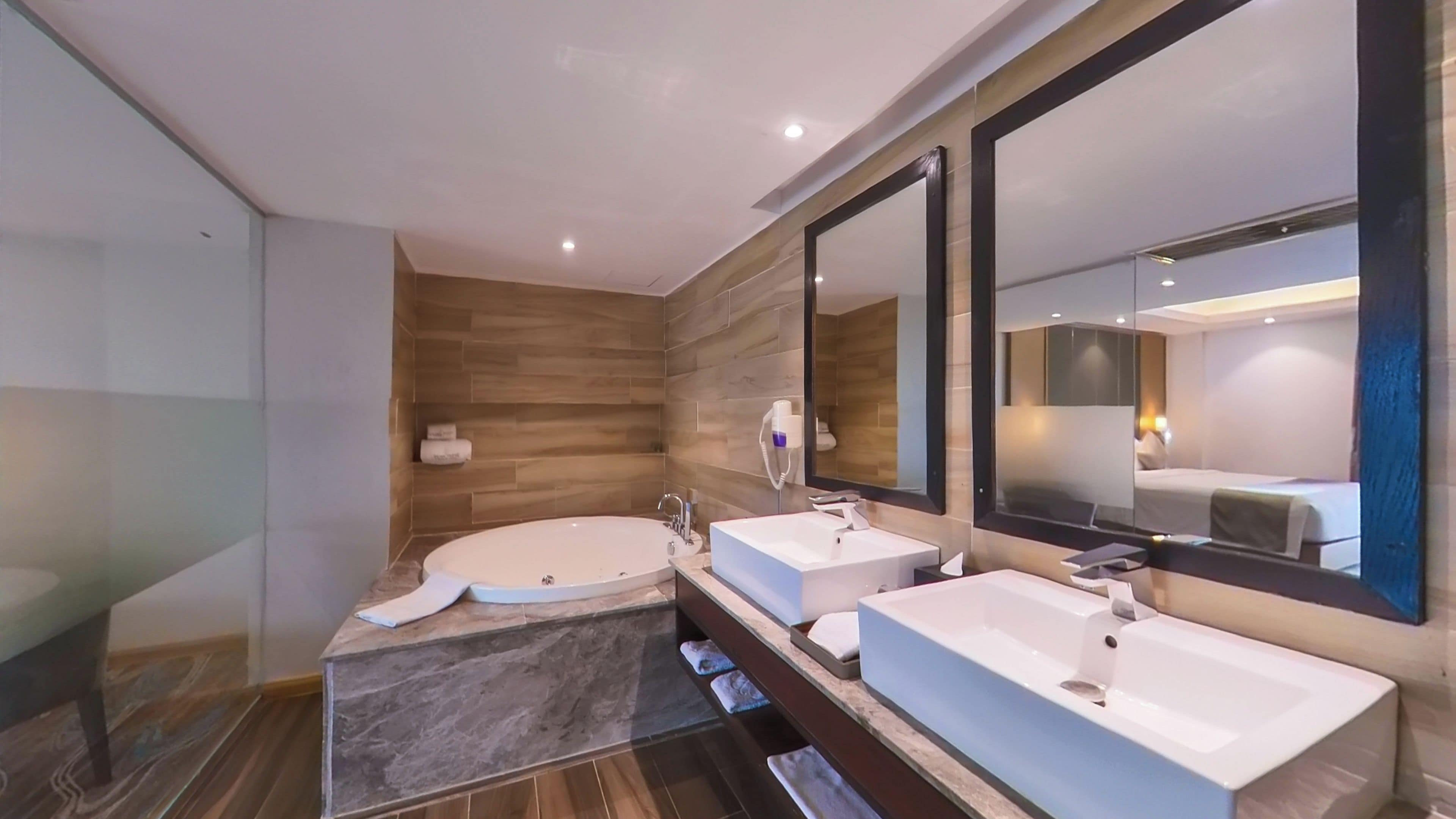 Un baño moderno con dos lavamanos, una bañera grande y un espejo.