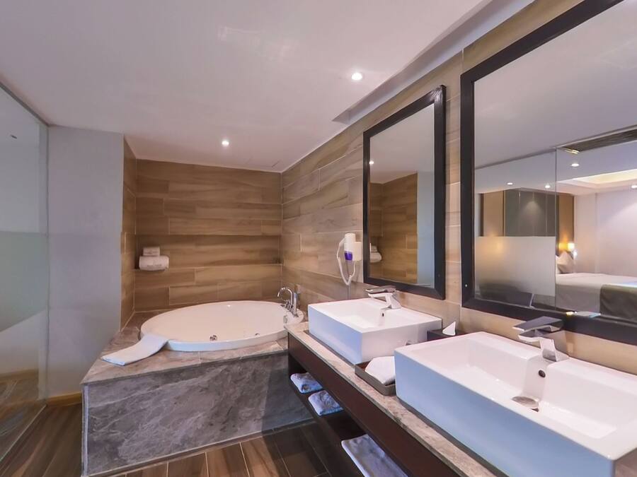 Un baño moderno con dos lavamanos, una bañera grande y un espejo.