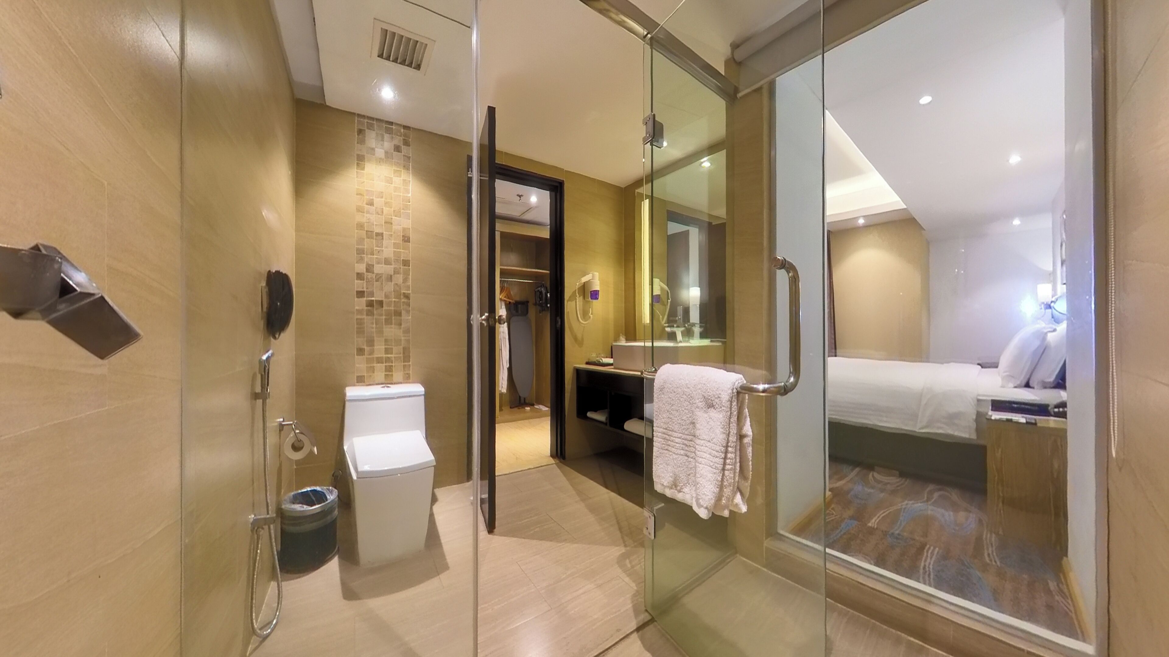 A modern hotel bathroom with a glass shower enclosure, a toilet, and a sink.