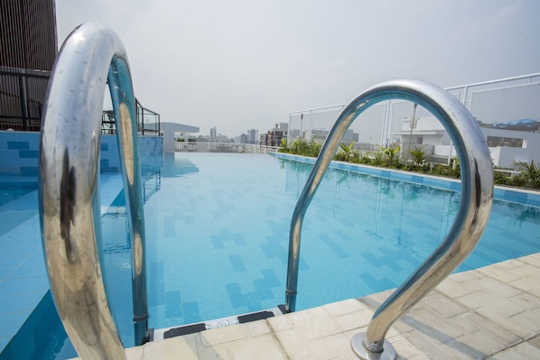 Une piscine dotée de rampes métalliques et d’un bord carrelé.